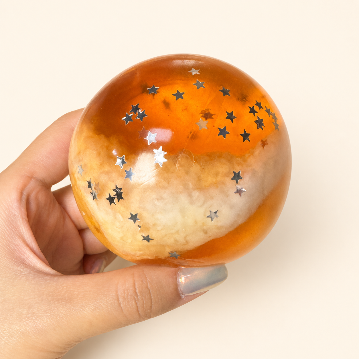 Hand holding the orange Amber Twilight Slush Sensory Ball